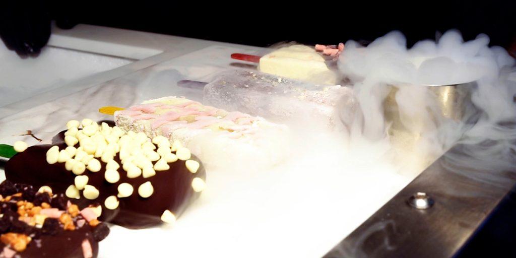 Artisan gelato and fruit ice lollies dipped in Belgian chocolate and white chocolate drops, served amidst billowing liquid nitrogen fog at a wedding dessert lolly lab station
