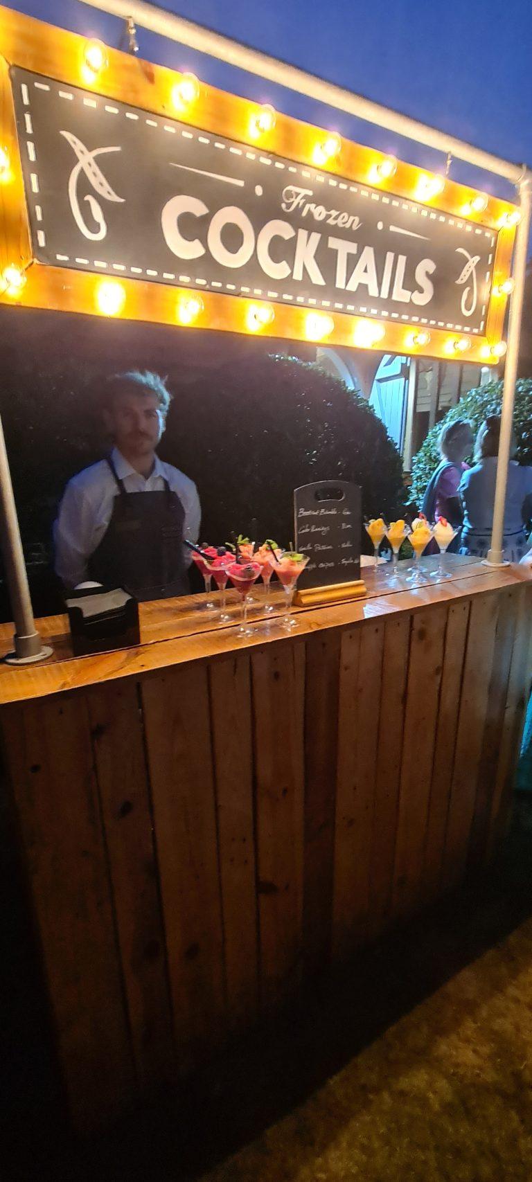 Evening wedding mobile cocktail bar illuminated by warm marquee filament bulbs