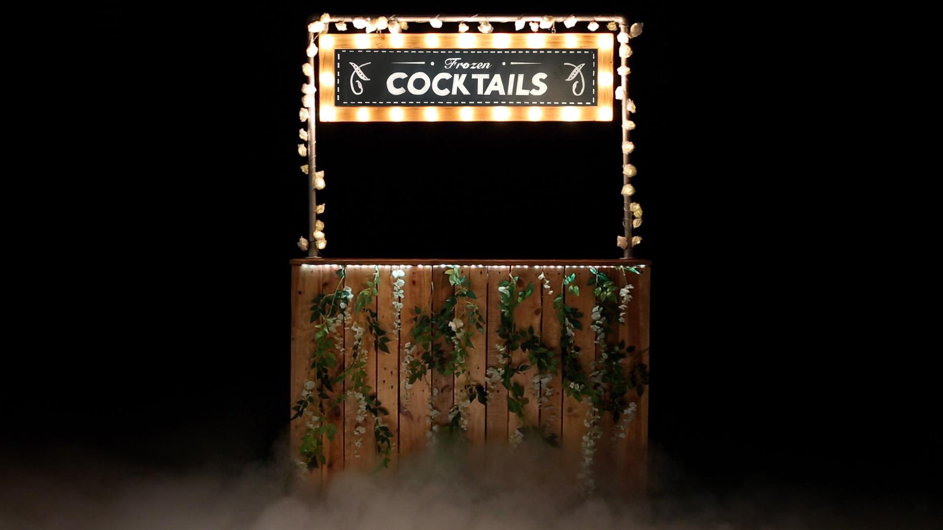 Rustic wooden modular mobile cocktail bar with illuminated Frozen Cocktails marquee sign and vapour mist