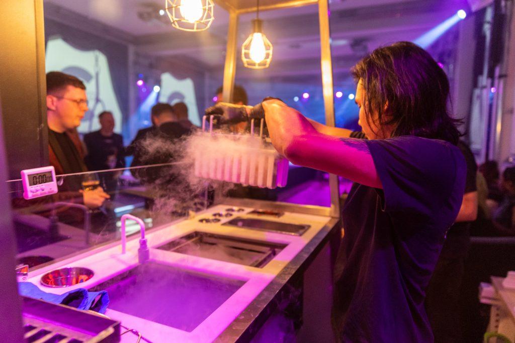 Chef lifting smoking flash-frozen liquid nitrogen ice lollies from cryogenic tank at Lolly Lab event bar