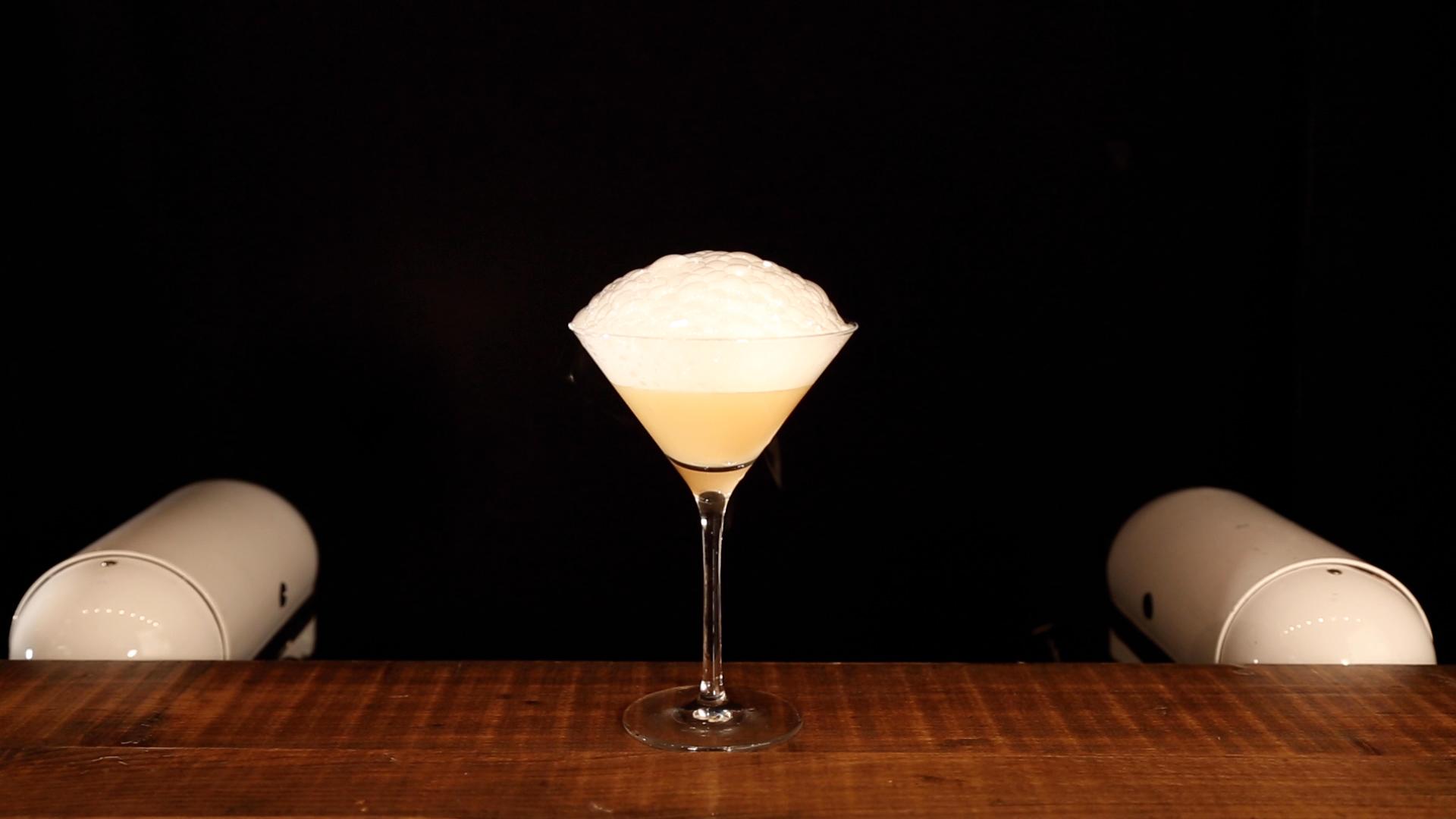 Molecular mixology cocktail topped with dense velvety culinary foam in a crystal martini glass