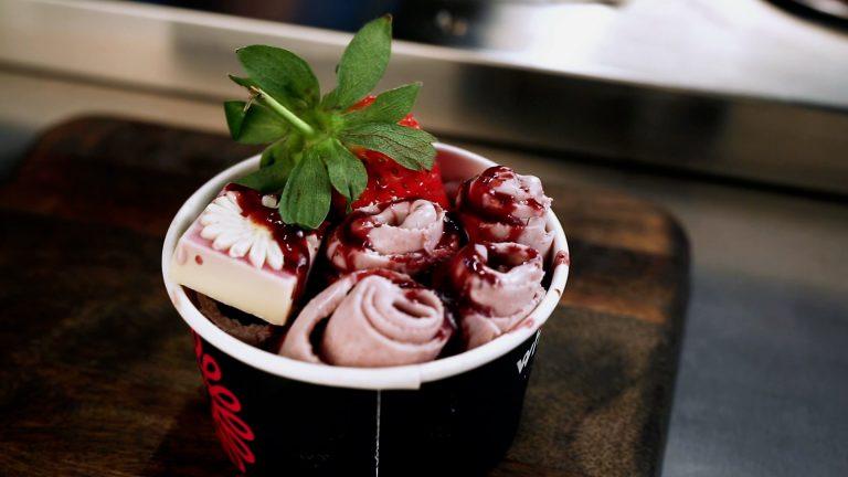 Rolled ice cream cup topped with fresh strawberries and chocolate