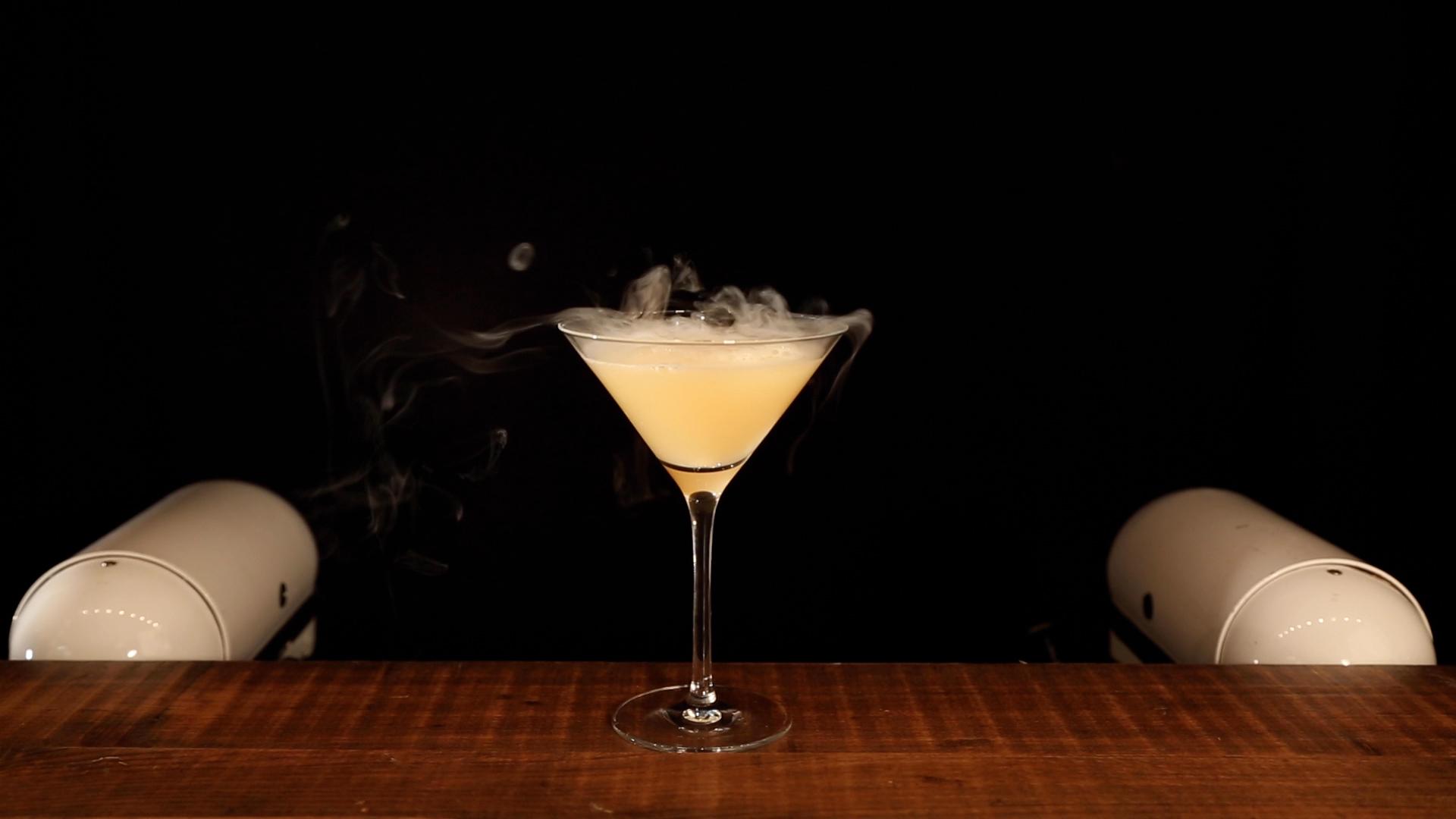 Theatrical vapourised botanical cocktail mist in an elegant martini glass on wooden mobile bar counter