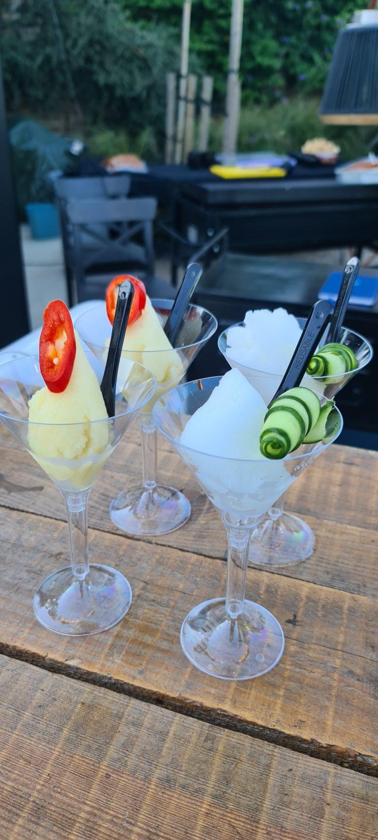 Stemmed coupe glasses filled with liquid nitrogen frozen cocktails and sorbet on rustic bar