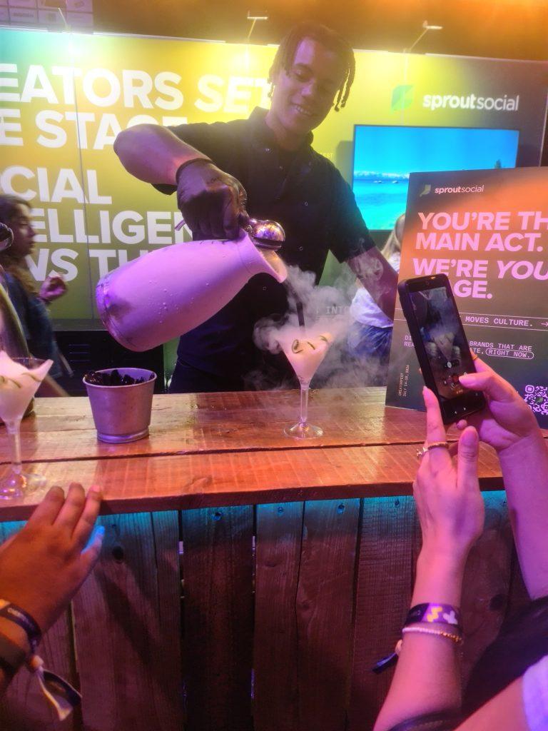 Mixologist pouring liquid nitrogen into cocktail glass with dramatic vapour cloud at wedding bar